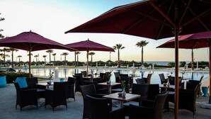 Espace extérieur aménagé avec des parasols, une piscine et des palmiers.