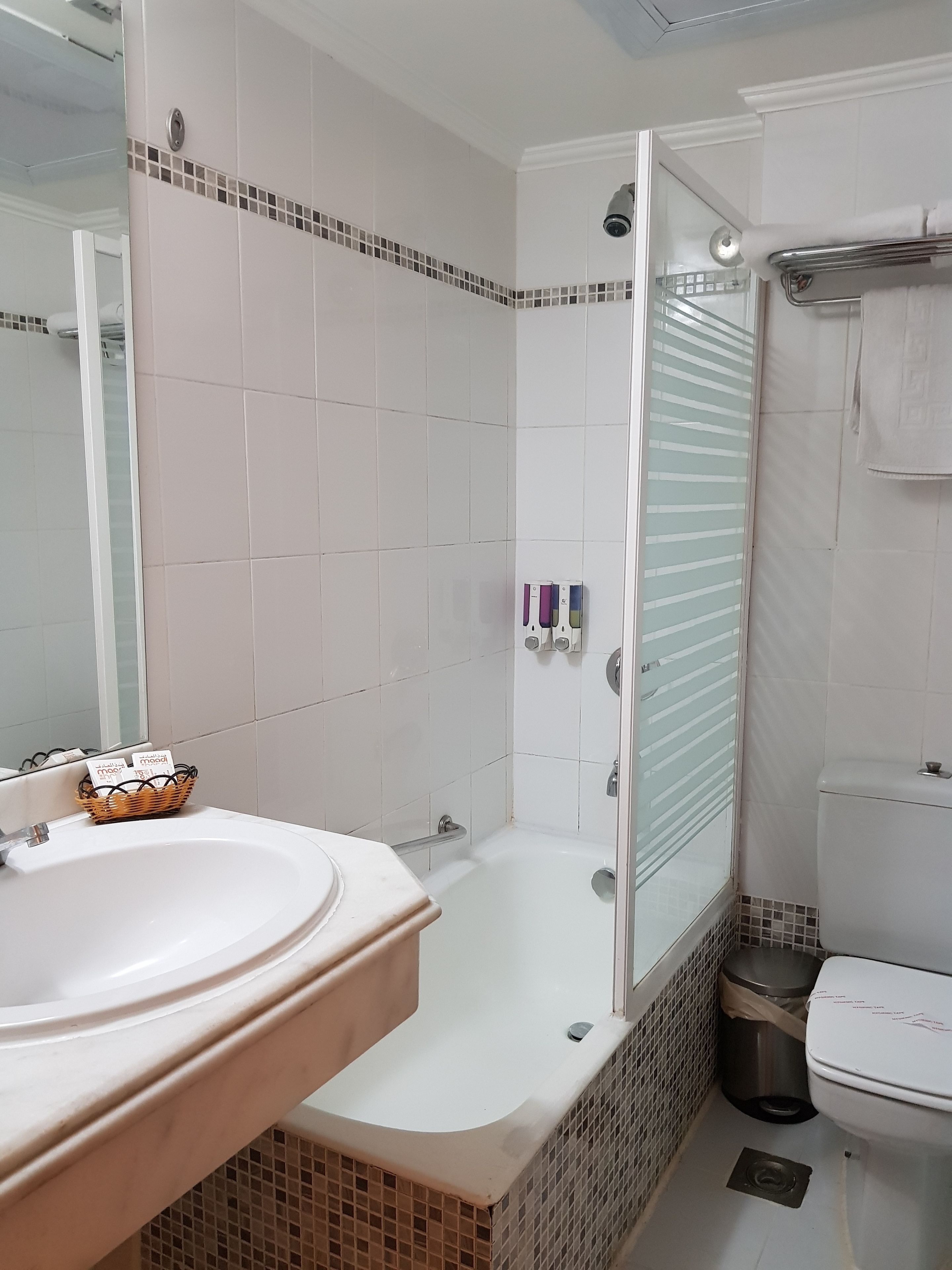A bathroom with a white sink, a bathtub, and a toilet. There is a glass shower door and a mirror on the wall.