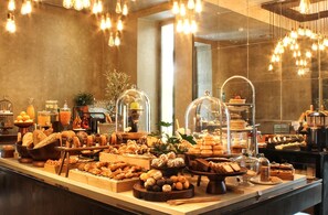 Un buffet proposant une variété de plats et un intérieur moderne agrémenté de luminaires suspendus.