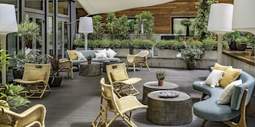 A modern outdoor seating area with wicker furniture, a blue sofa, and potted plants.
