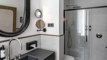A modern bathroom with a large mirror, a sink with a towel rack, a toilet, and a shower area.