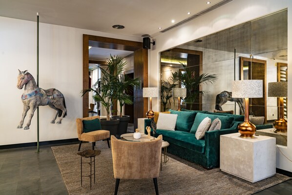 Un salon moderne avec un canapé vert, une sculpture de cheval et un grand miroir.