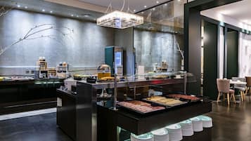 Un espace buffet proposant une variété de plats, une cloison en verre et un aménagement intérieur moderne.