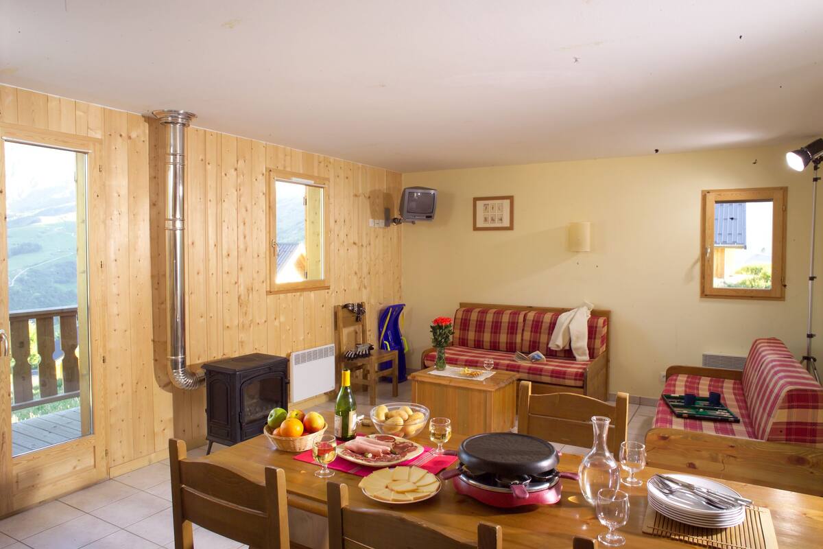A wooden interior with a dining table set for a meal, a sofa, and a fireplace.