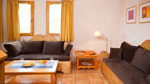 A cozy living room with a sofa, a wooden coffee table, and a small side table with a lamp. - Résidence et Chalets de la Fontaine du roi  (Saint-Jean-d'Arves)