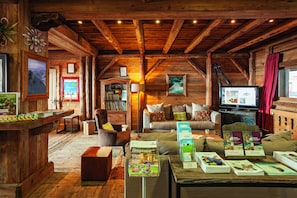 Un acogedor interior de cabaña de madera con techo de madera, un sofá, una mesa de centro y una televisión.