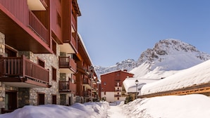 A snow-covered mountain path leading to a building with balconies and stone walls. - Residence Pierre & Vacances Premium L'Ecrin des Neiges (Tignes)