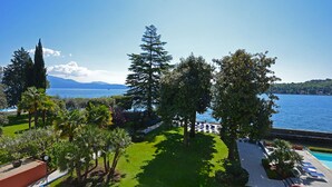 A landscaped garden with a pool, trees, and a view of a lake and mountains. - Hotel Salo' du Parc (Salò)