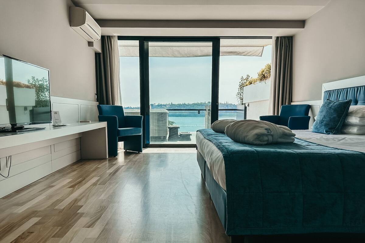A modern hotel room with a large bed, a desk, a chair, and a TV.
