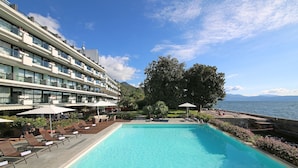 A hotel with a swimming pool, sun loungers, umbrellas, and a view of the sea. - Hotel Salo' du Parc (Salò)