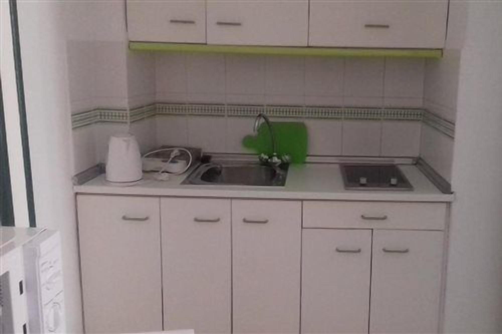 A kitchen with a sink, a stove, and cabinets.