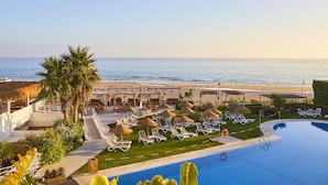 A resort pool area with lounge chairs and umbrellas, a palm tree, and a view of the beach and ocean. - FERGUS Conil Park (Conil de la Frontera)