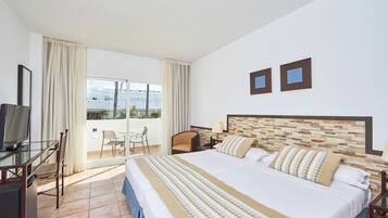Een hotelkamer met een groot bed, een televisie, een bureau met stoel, en een balkon met een stoel.