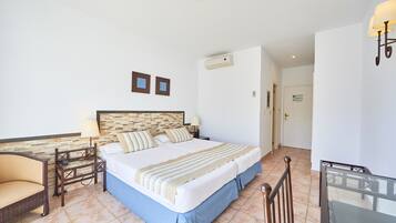 Una habitación de hotel con cama, escritorio, silla y mesa de vidrio.