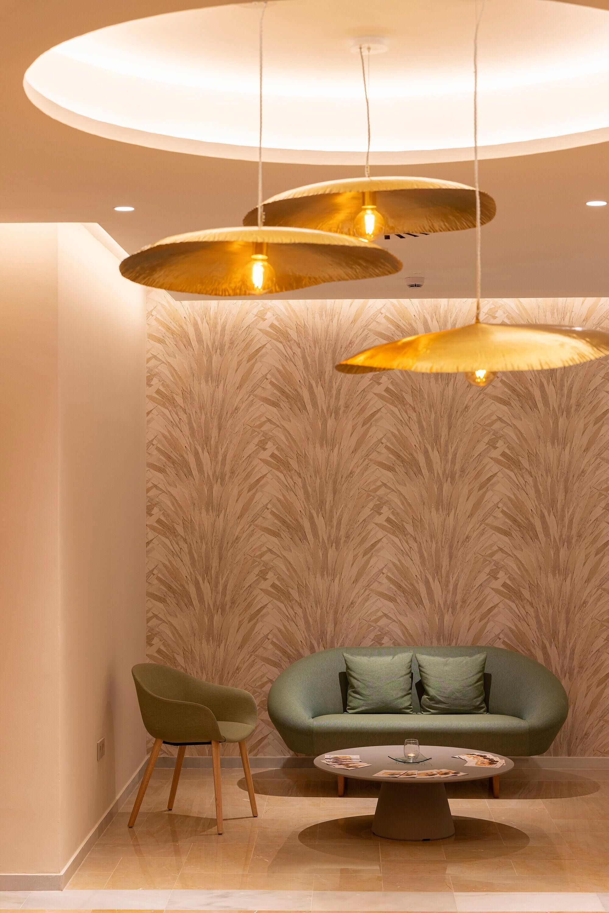 A modern interior with a green sofa, a round table, and three pendant lights.