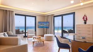 Una habitación de hotel moderna con un balcón grande, un televisor de pantalla plana, un comedor y vistas al mar.