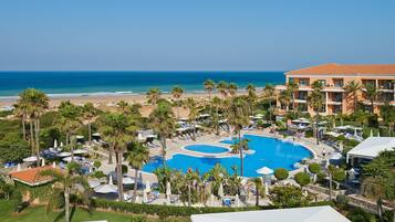Un resort con una piscina grande, acceso a la playa y vista al océano.