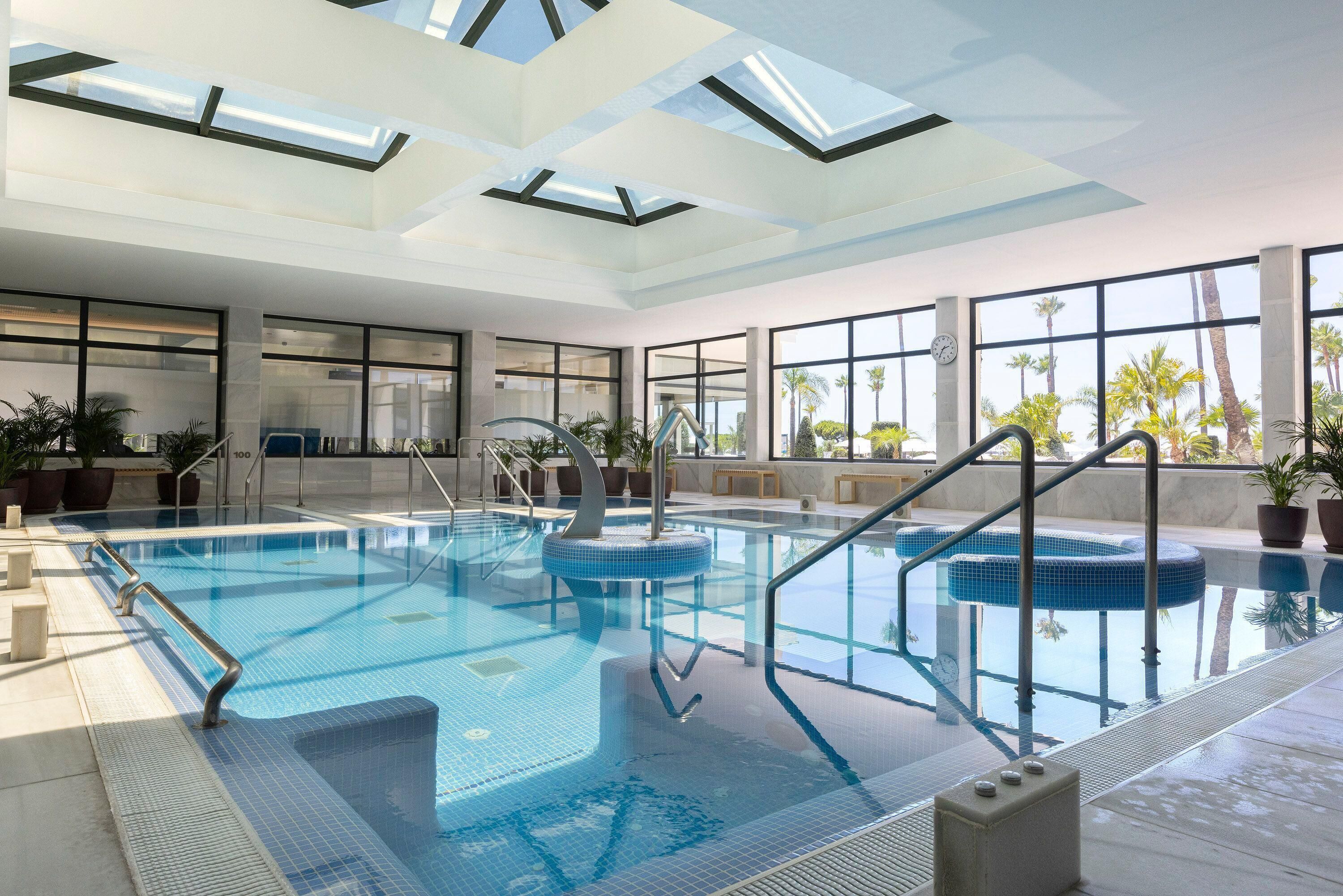 Ein Hallenbad mit großen Glaswänden, Fliesenboden und modernem Design.