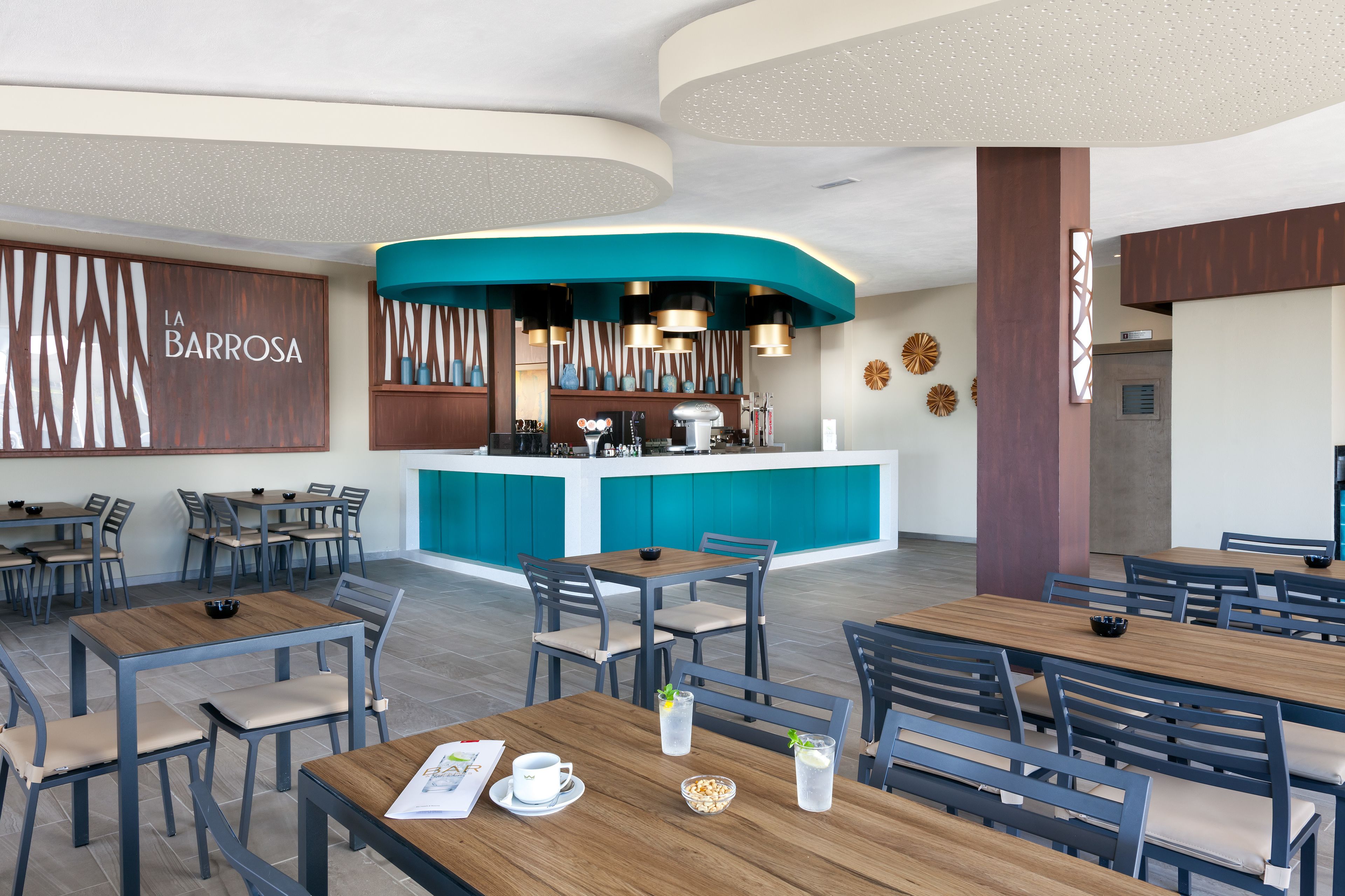 Un restaurante moderno con zona de bar, varias mesas y sillas para comer.