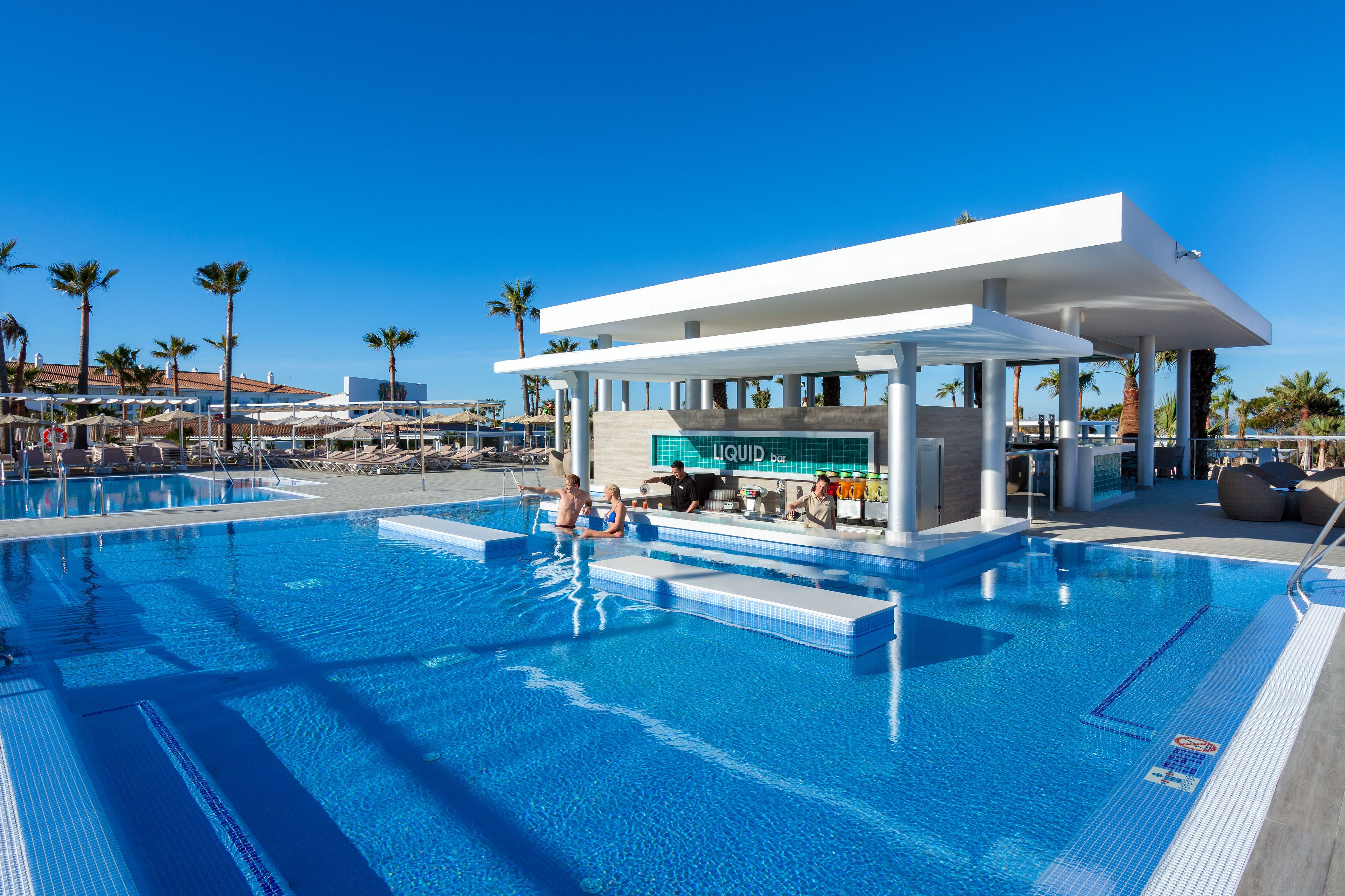A modern pool area with a bar and lounge chairs.