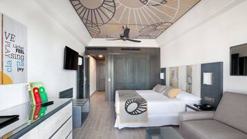 Una habitación de hotel moderna con cama, sofá, escritorio con teléfono y televisor.