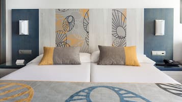 Un lit double avec deux oreillers, une table de chevet avec un téléphone et un mur décoré d’œuvres d’art abstraites.
