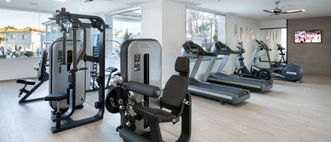 A modern gym with ceiling fans, treadmills, and weight machines.