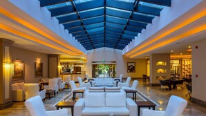 A spacious lobby with a high ceiling and a glass roof, featuring a bar area and seating arrangements. - Aydinbey Famous Resort - Ultra All Inclusive (Serik)