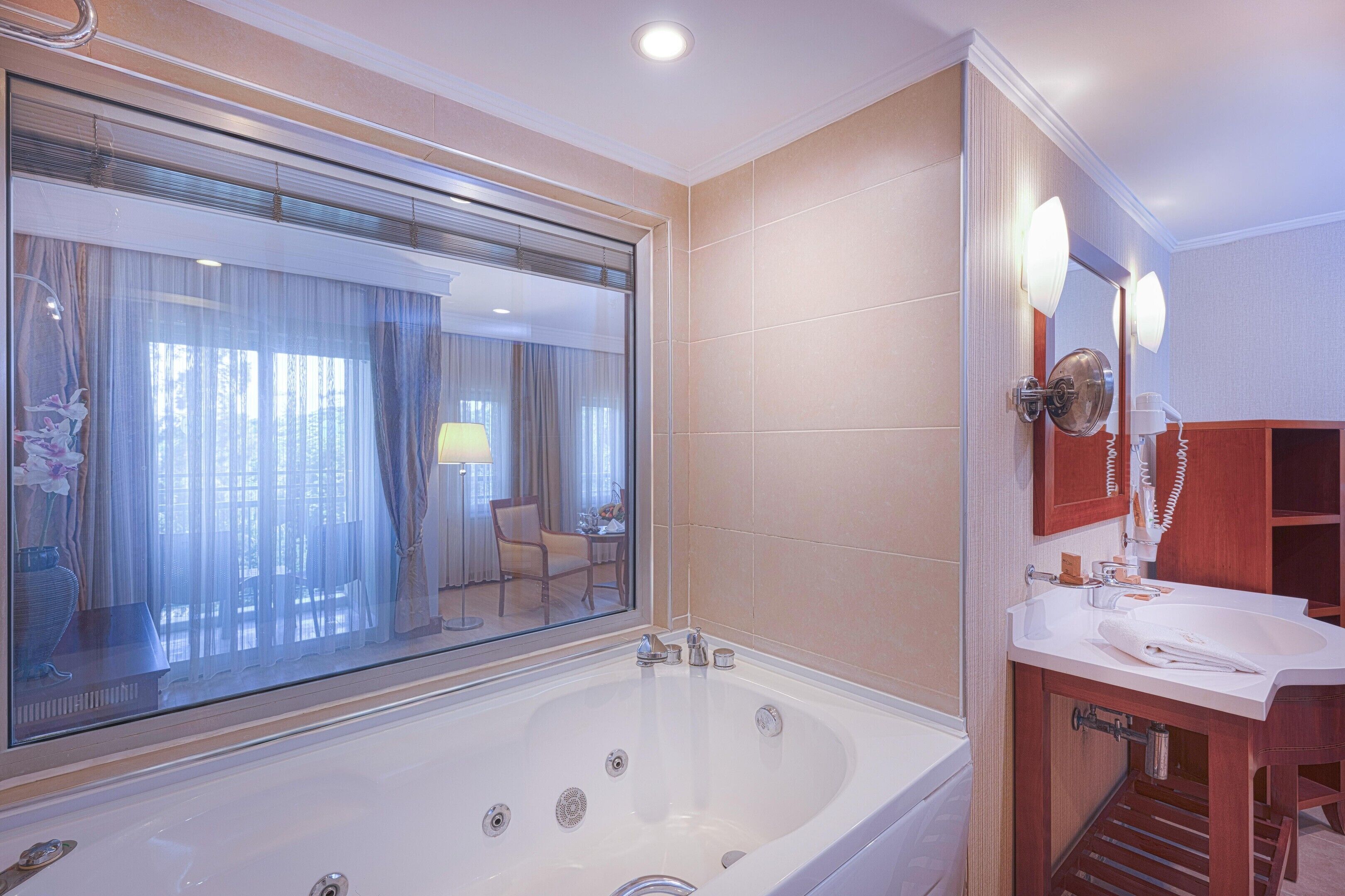 A modern bathroom with a large bathtub, a mirror, and a vanity with a sink.