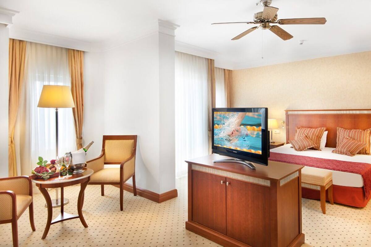 Ein Hotelzimmer mit Bett, Fernseher, Schreibtisch und Stuhl.
