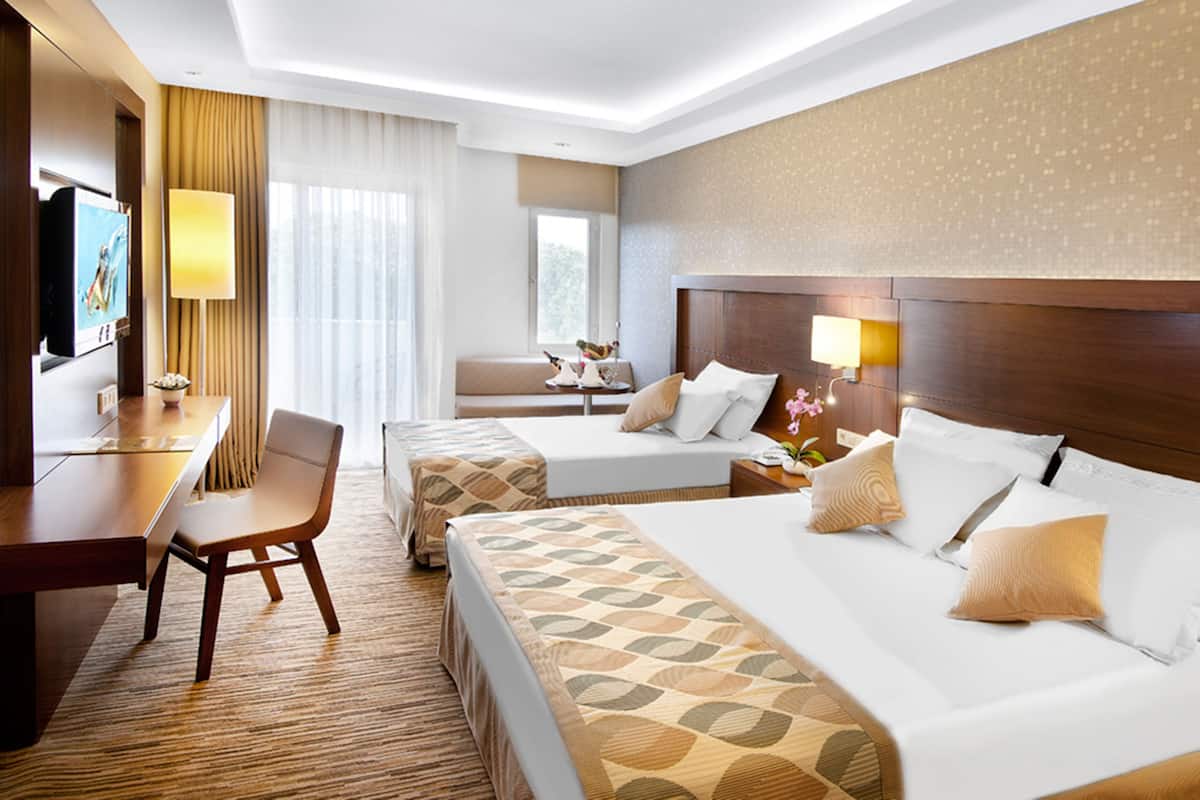 Ein Hotelzimmer mit einem großen Bett, einem Schreibtisch, einem Sessel und einem kleinen Tisch.