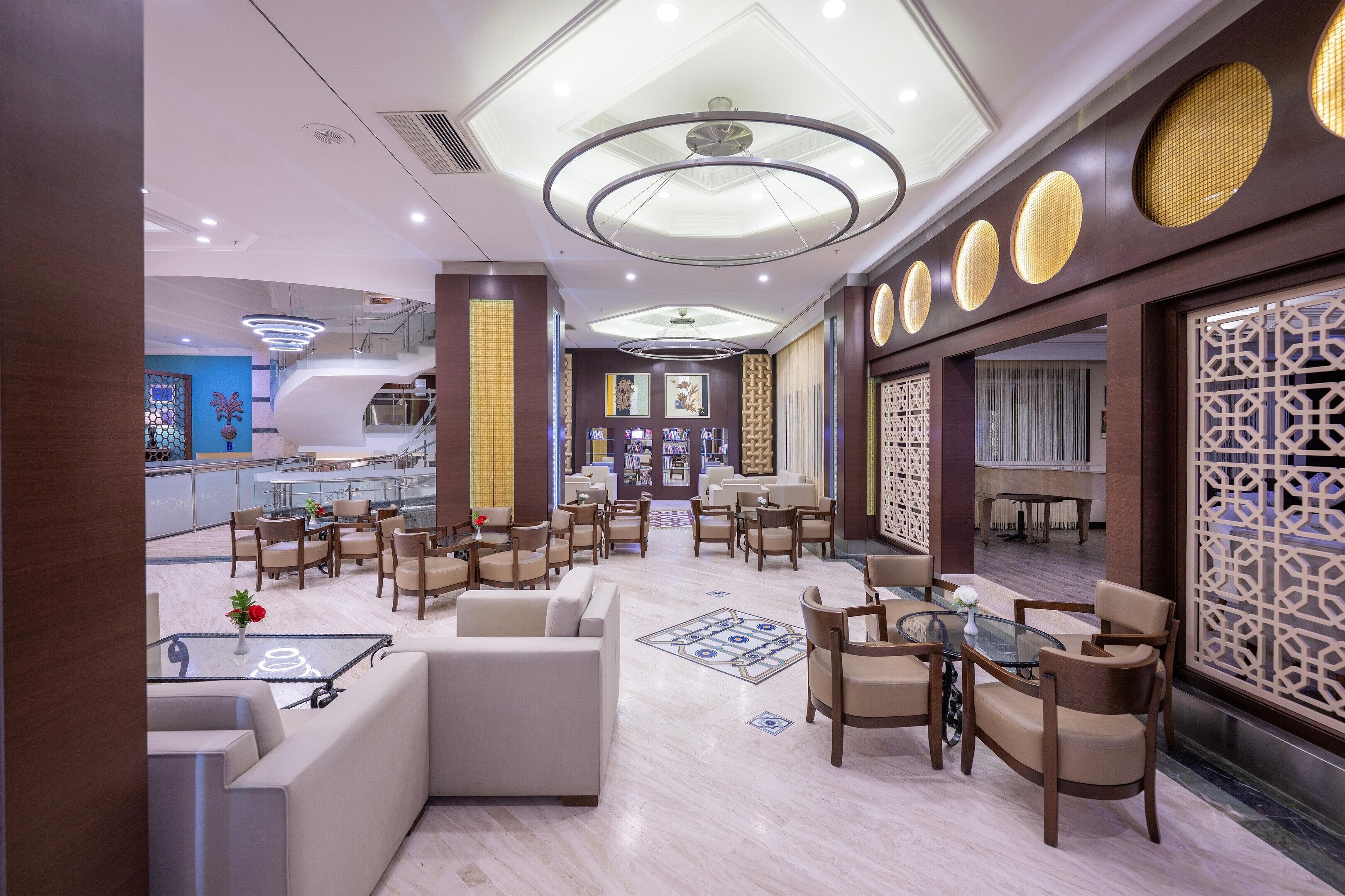 A hotel lobby with a modern design, featuring a seating area with sofas and chairs, a reception desk, and a decorative wall with circular patterns.