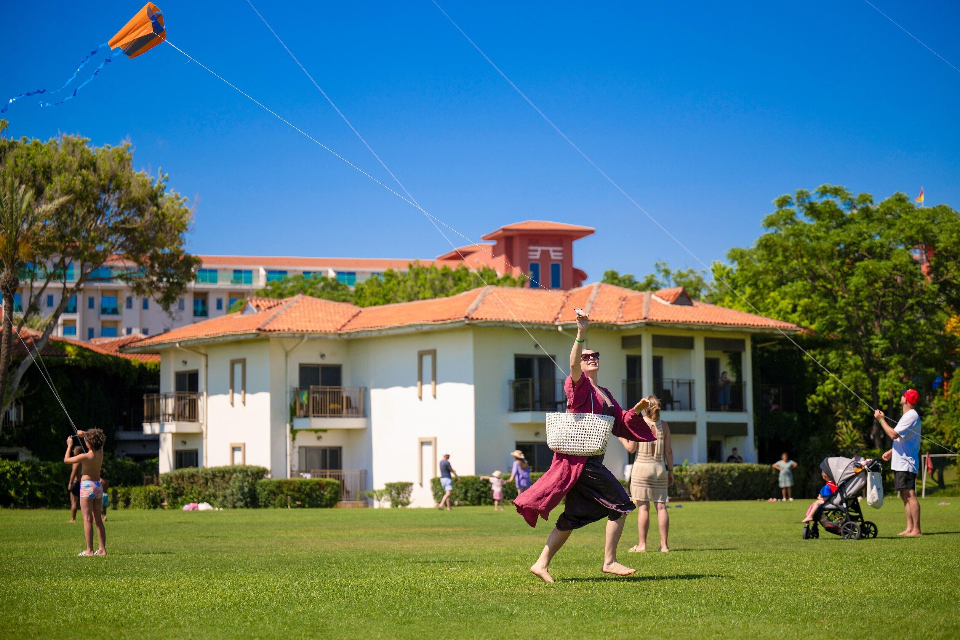 A grassy area with a building in the background, a kite, and people.