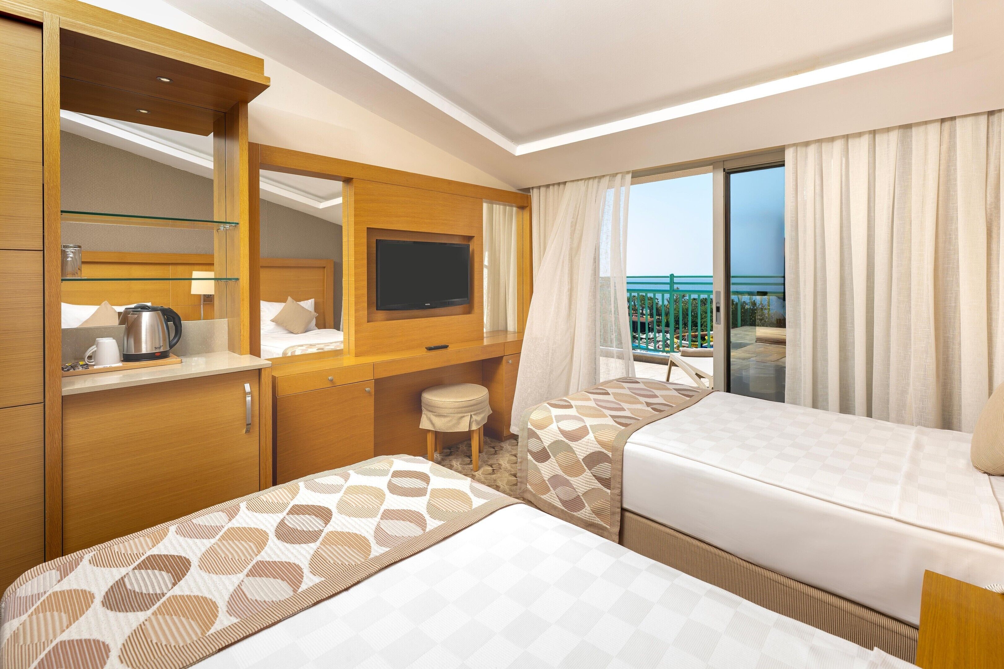 Une chambre d’hôtel avec deux lits, une télévision, un minibar et un balcon avec vue.