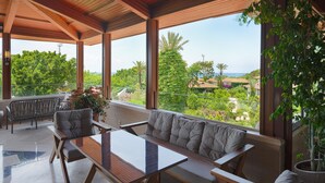 Ein geräumiger Balkon mit Holzboden, einem Glastisch und einer gepolsterten Bank.