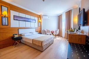 A hotel room with a large bed, bedside tables, a desk, a chair, and a TV.