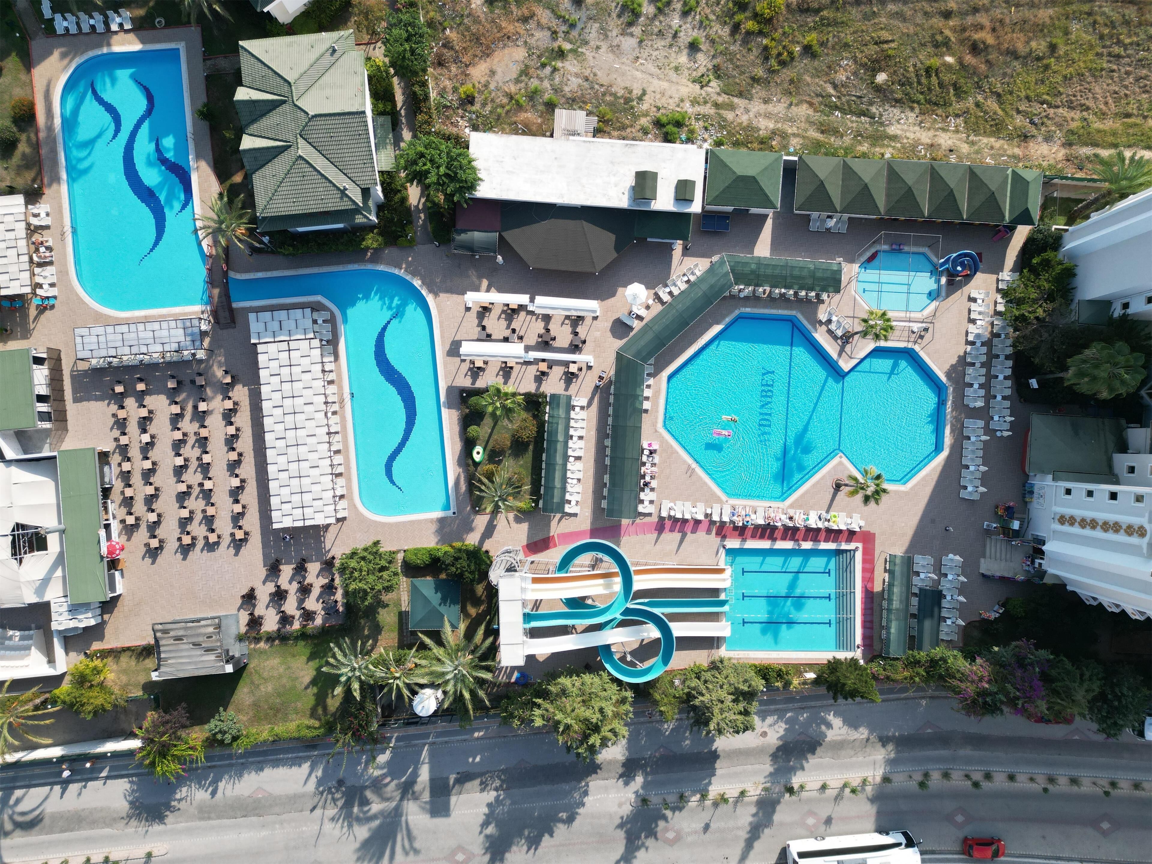 Luchtbeeld van een resort met diverse zwembaden, ligbedden en een glijbaan.