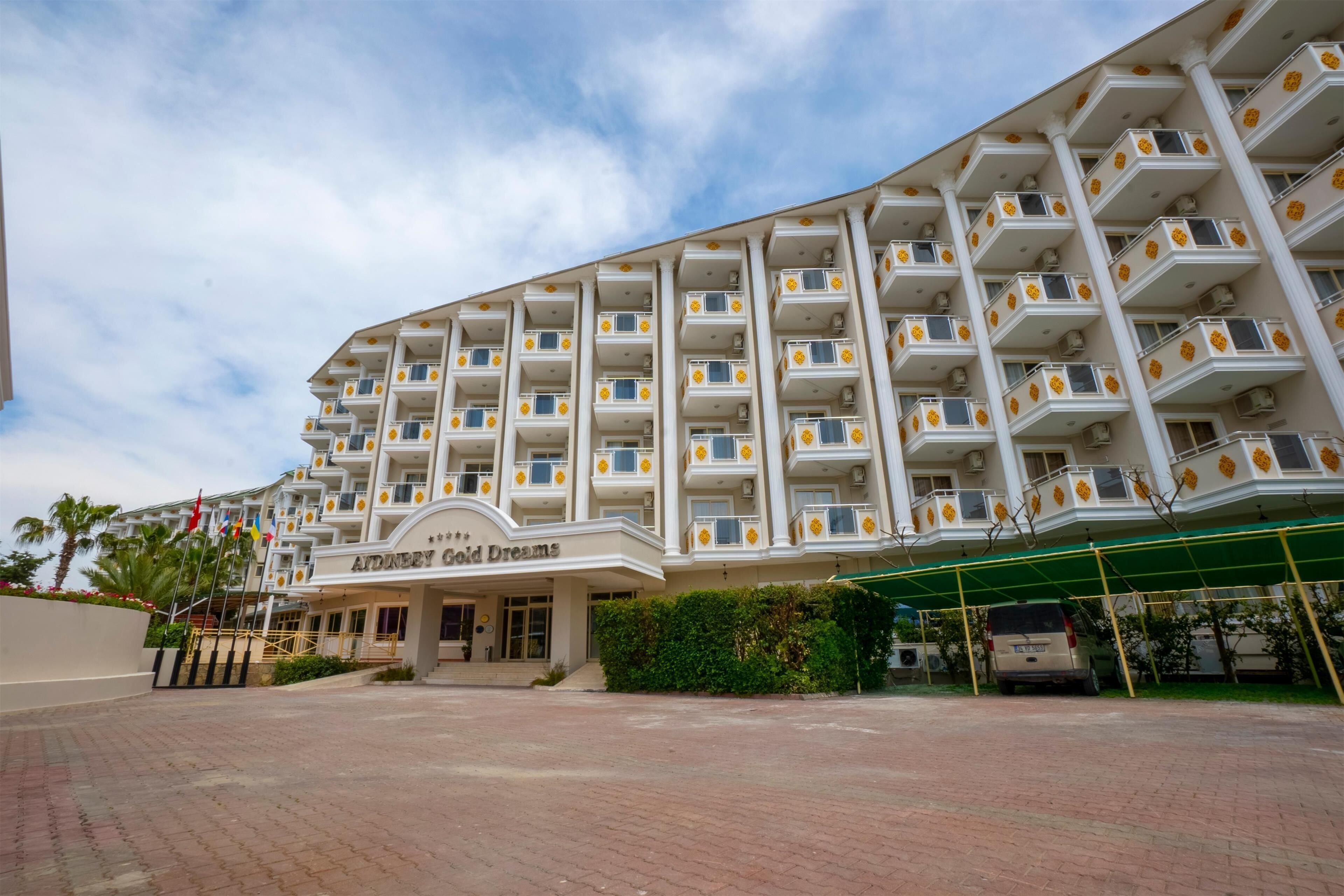 Een hotel met meerdere verdiepingen, balkons, een overdekte ingang en een verharde oprit.