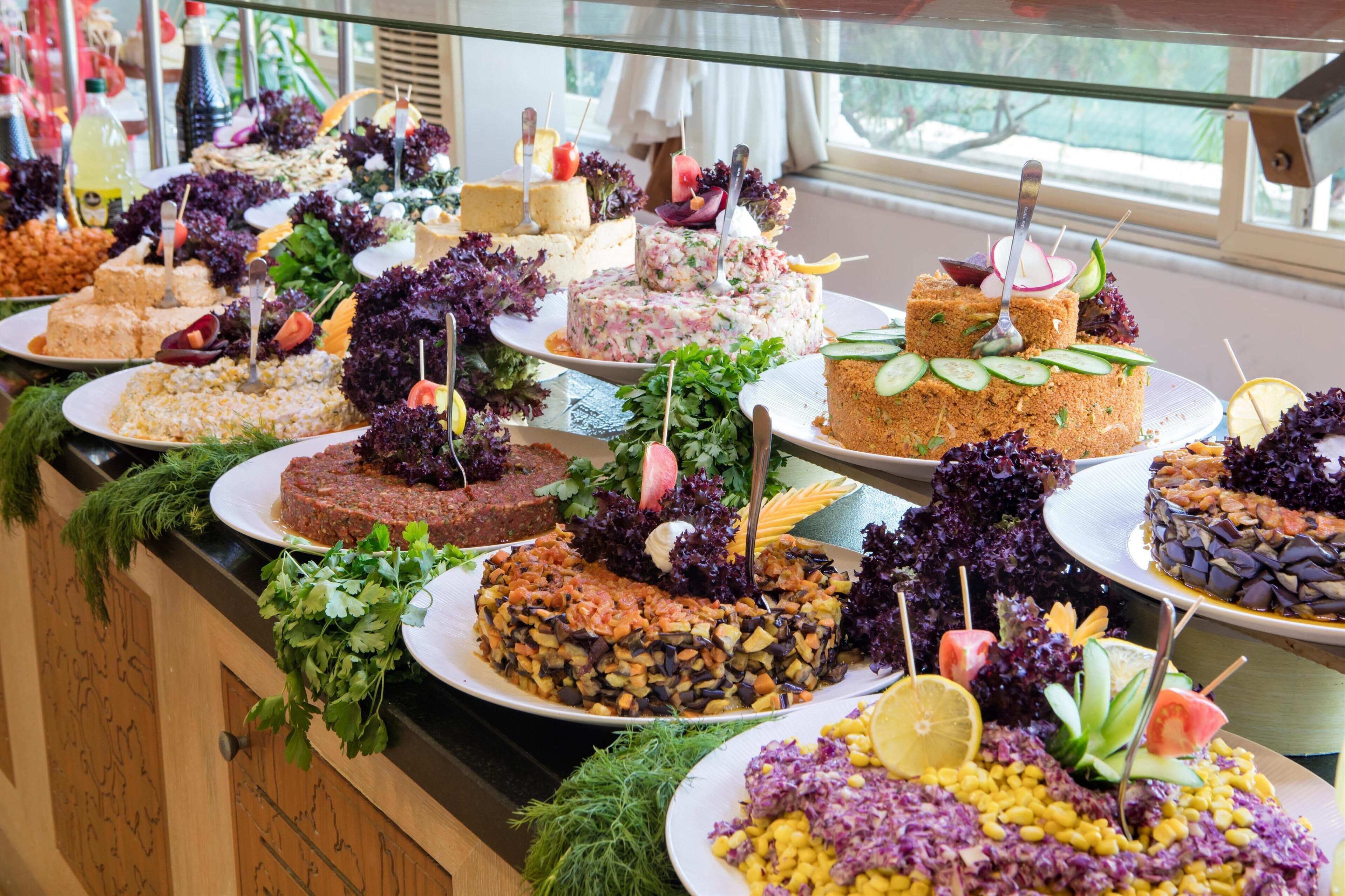 Un buffet proposant une variété de plats, notamment des salades, des viandes et des desserts, disposés sur un comptoir.