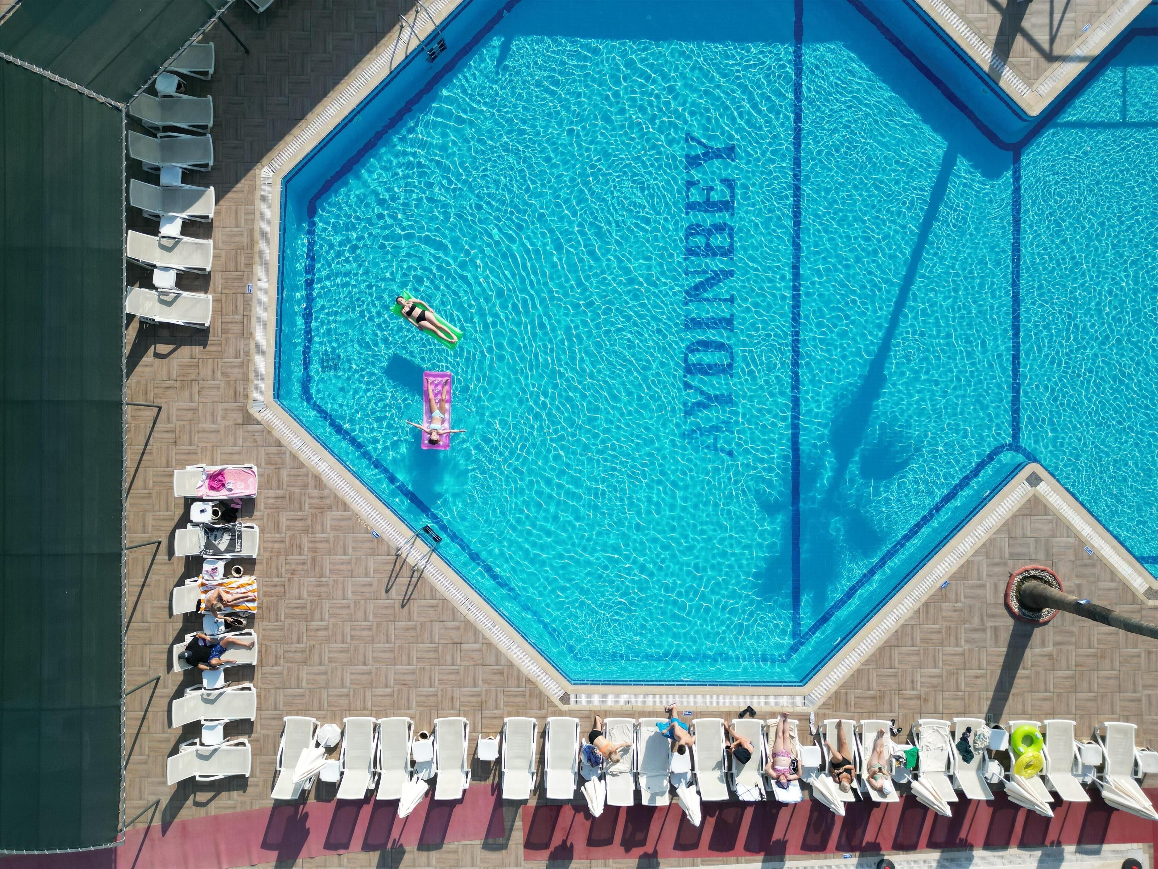 Una piscina grande y azul, con sillas de descanso y sombrillas dispuestas alrededor.