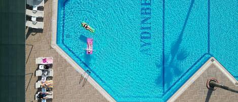 Una piscina grande y azul, con sillas de descanso y sombrillas dispuestas alrededor.