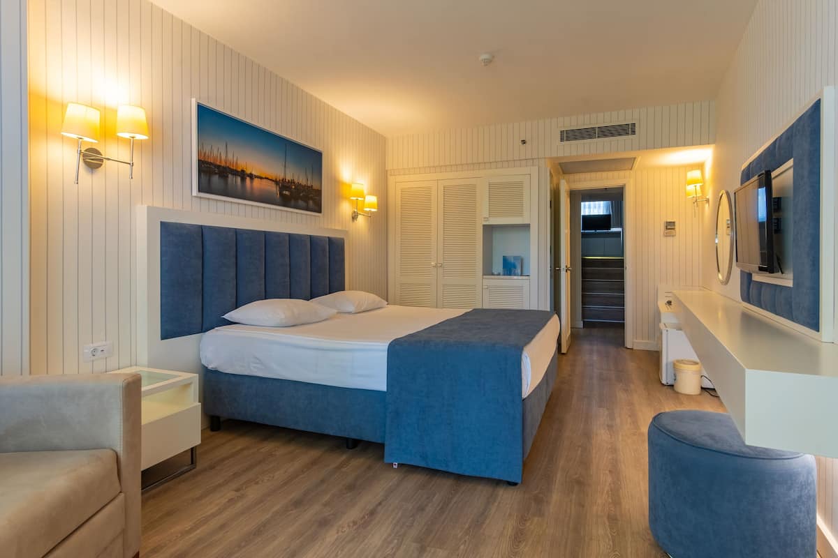 Una habitación de hotel moderna con una cama grande, mesitas de noche, un escritorio y un televisor.