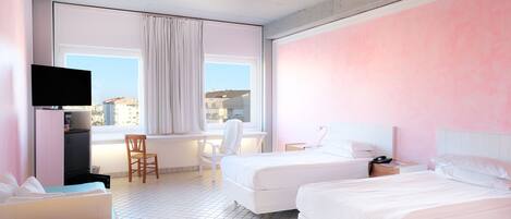 A hotel room with two beds, a desk, a chair, a TV, and a window with curtains.