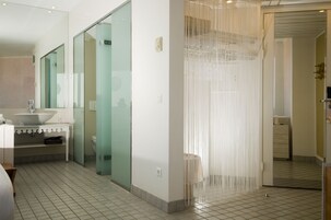 Un baño moderno con un espejo grande, un lavabo y una zona de ducha.