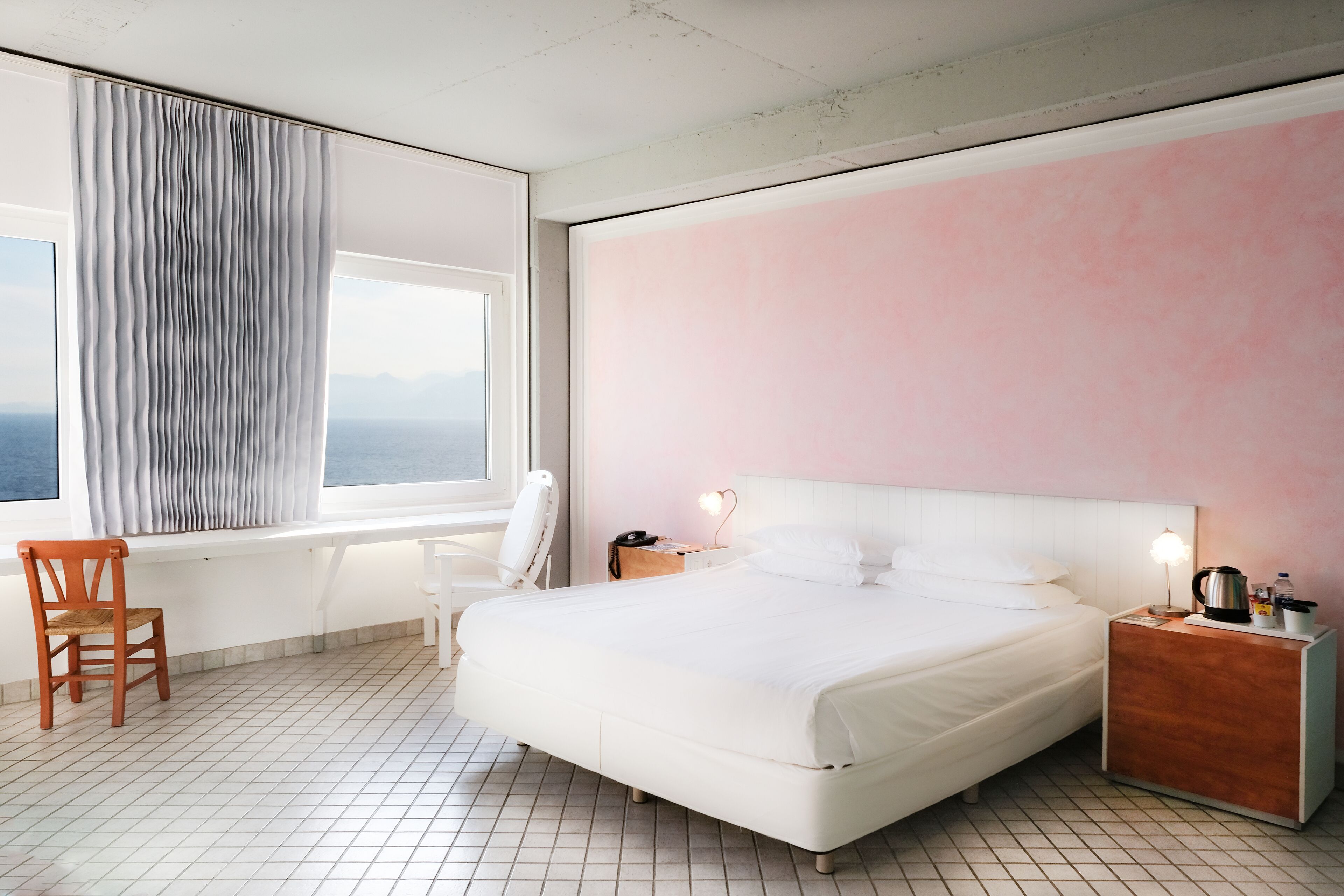 A modern hotel room with a large bed, a desk, and a chair.