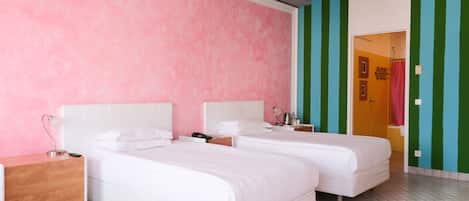 A hotel room with two beds, a wooden nightstand, a white dresser, and a bathroom visible through an open door.