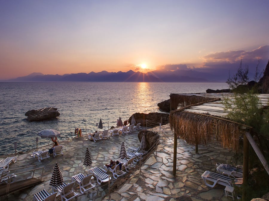 Na praia, espreguiçadeiras, guarda-sóis, toalhas de praia