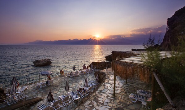 En la playa, sillas reclinables de playa, sombrillas, toallas de playa