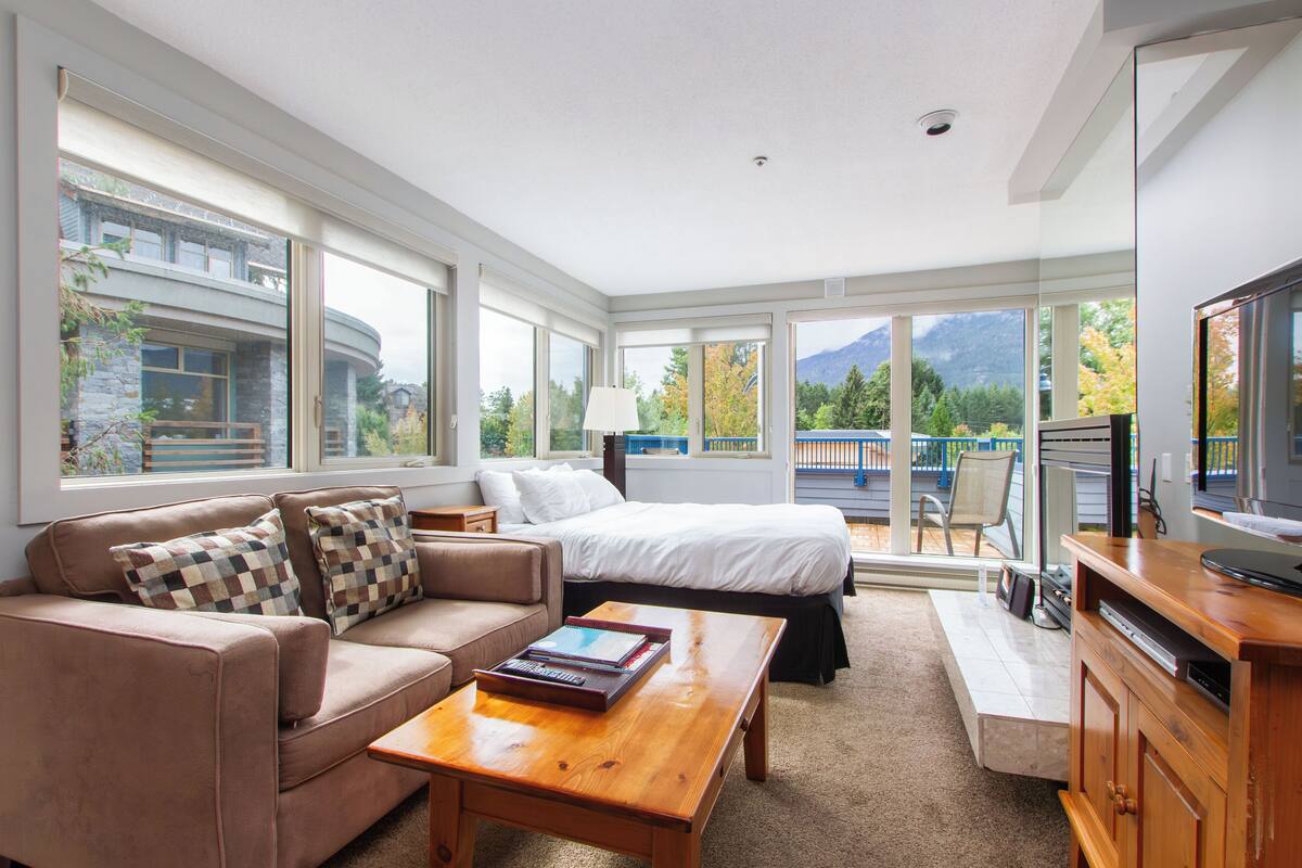 A modern bedroom with a large bed, a sofa, and a TV.