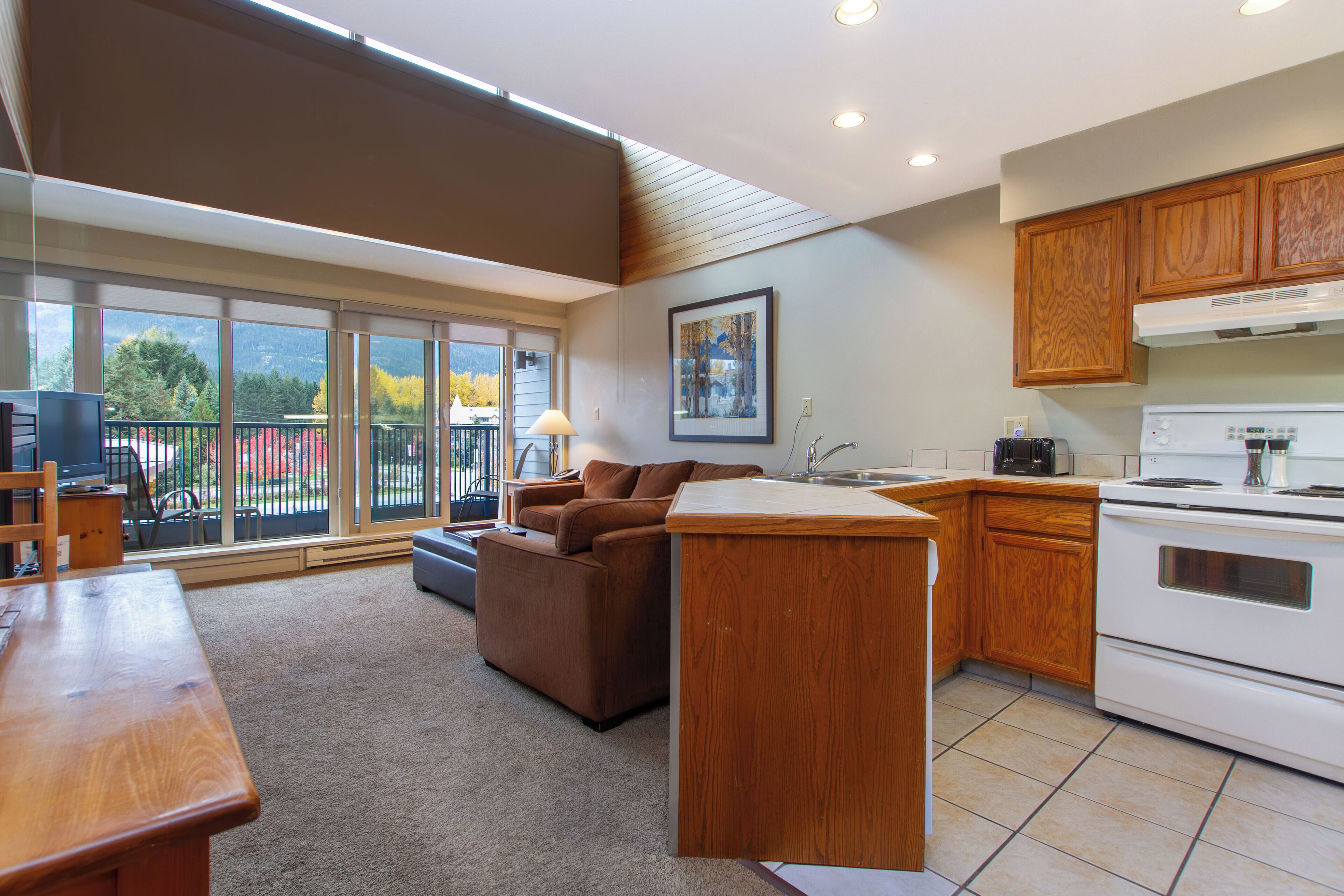 A modern kitchen with wooden cabinets, a built-in oven, and a dining area with a table and chairs.